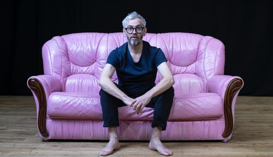 A man sat on a pink leather sofa