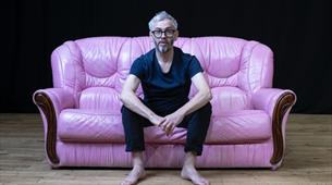 A man sat on a pink leather sofa 