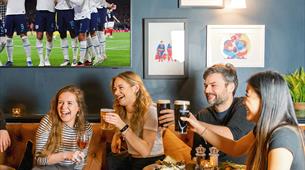 A group of people enjoying a pint watching the football 
