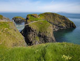 Carrick-a-rede Rope Bridge on a sunny day with the ocean crashing below