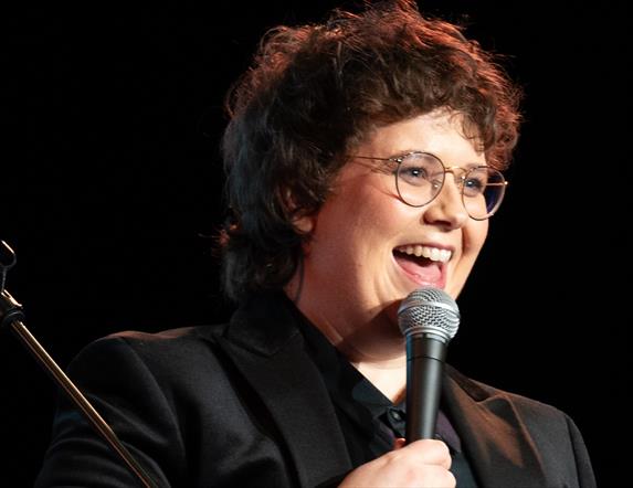 Picture of Emer Maguire laughing holding a microphone.