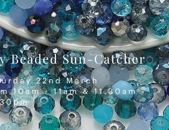 An image with many blue, turquoise and azure beads spilling out from a white porcelain bowl. White text on the front reads "Sky Beaded Sun Catcher" on