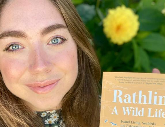 Ruby Free holding up her book, "Rathlin Wildlife" for the camera.