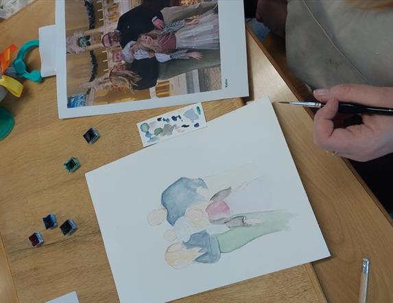 A person painting a family photo using watercolours.
