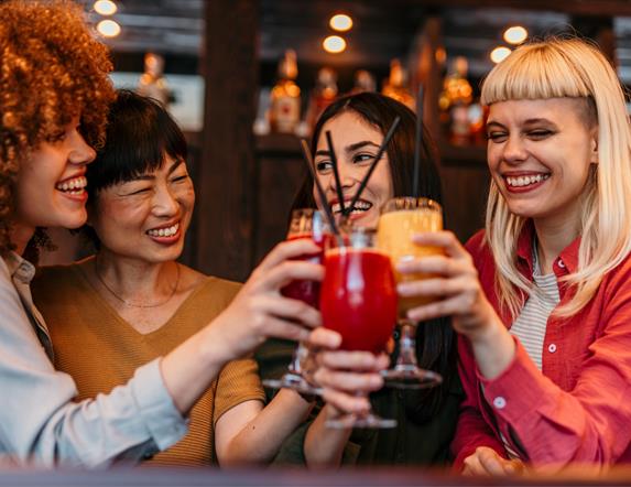 a group of women raise glasses of cocktails together
