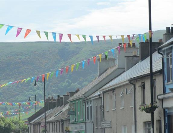 Cushendall street with various coloured flags strung between lamp-posts.
