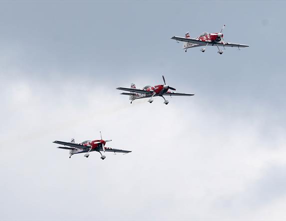 three red and white planes flying together through the sky