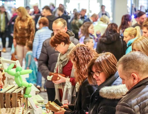 people browsing busy market stalls indoors