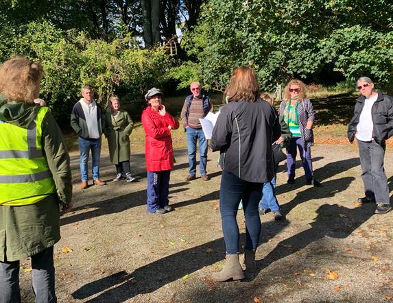 a group of people stand outdoors listening to a tour guide