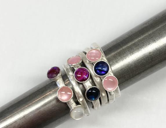A number of silver rings all stacked together, encrusted with a number of semi precious stones ranging.