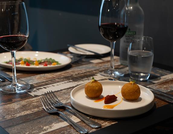 Italian dishes and red wine sit on a restaurant table