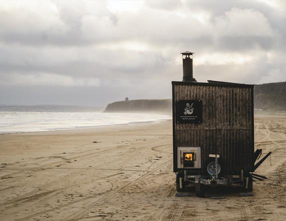 sauna standing on a beach backed by cliffs