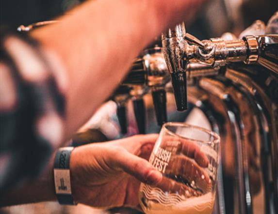Image shows a man pouring a pint of beer in a 'Portrush Beer Fest' branded glass
