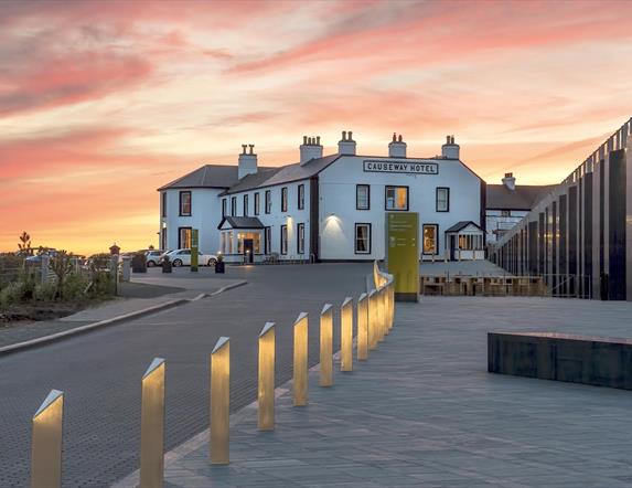 The Causeway Hotel bar accompanied by a beautiful pink and orange sunset in the background.