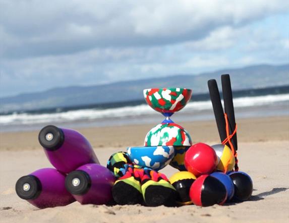 juggling props sit on a beach with the ocean in the background