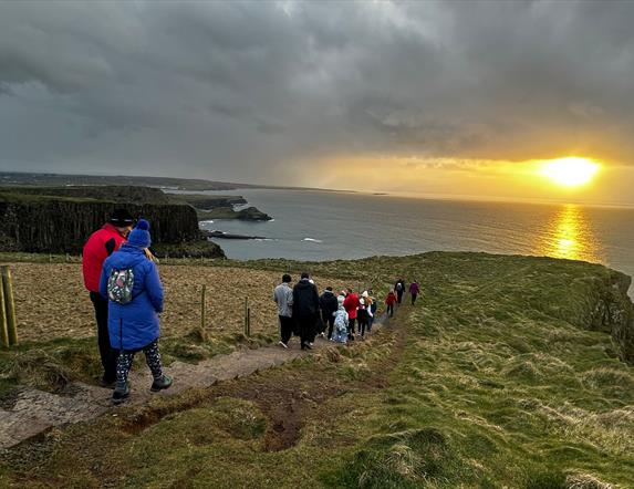 Visitors admiring the sunrise on the Causeway cliffs