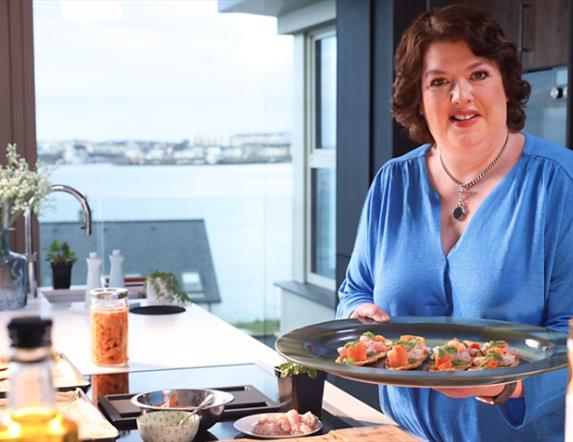 Paula McIntyre stands with plate of canapes in a kitchen