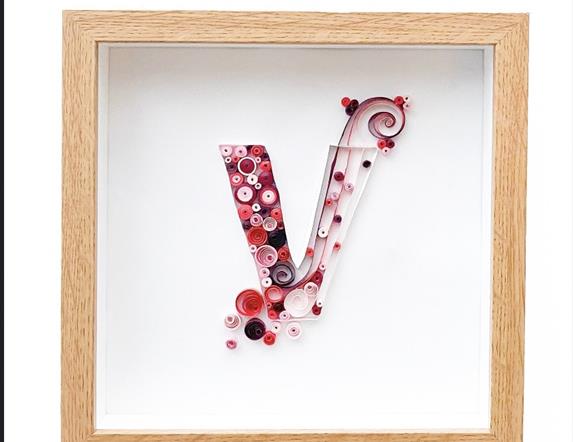 Quilled letter V, filled with colourful shapes and coils made from paper