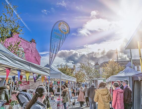 A sunny blue sky looks down on the top of white tent stalls and smiling crowds at the Roe Valley.