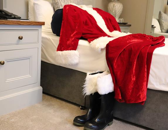 Santa's red suit and boots on a bed at The Causeway Hotel