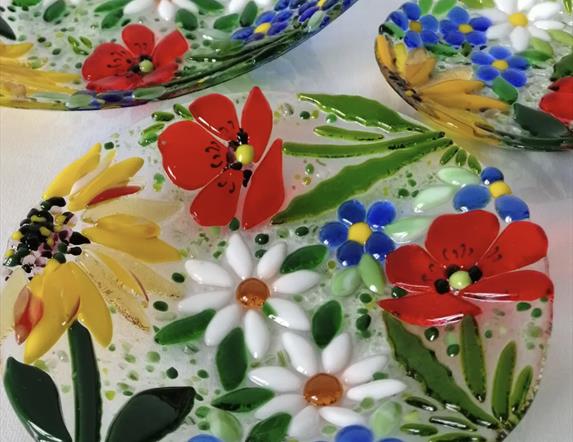 A glass plate decorated with colourful glass flowers.