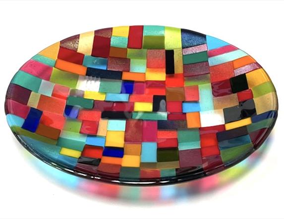 A shallow glass dish made from various different colours arranged in geometric patterns.