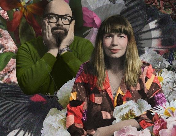 Rachel McCarthy and Michael Keeney post in front of a colourful background of flowers and patterns.