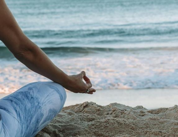 A person sitting in a relaxing pose at a beach with an ocean view