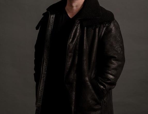 Image of a man wearing a long black coat laughing