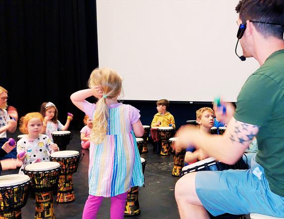 A small class of children being instructed on small drums by James Hamilton.