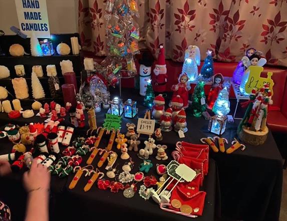 a table at a christmas market filled with hand crafted gifts and candles