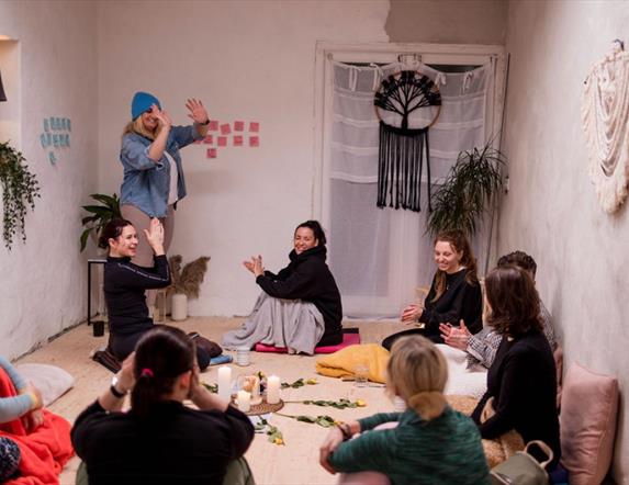 group of women in a room talking and joing their palms together