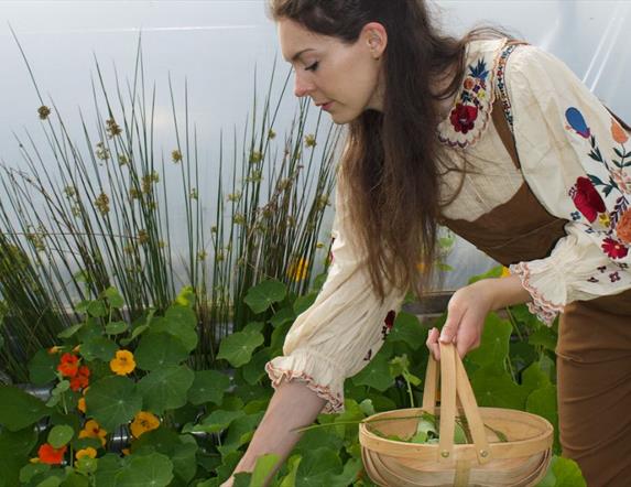 a person holds a wicker basket while reaching for plants