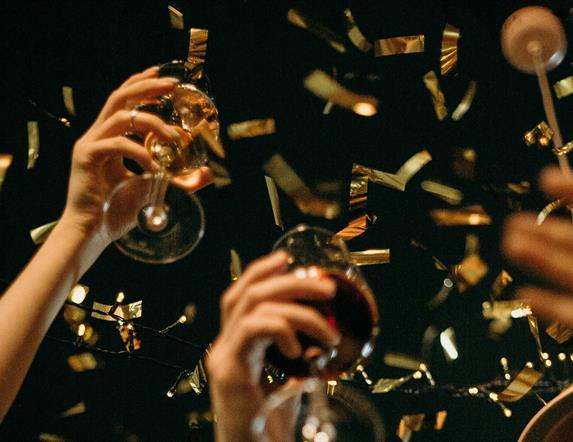 people raising their glasses as gold confetti falls around them