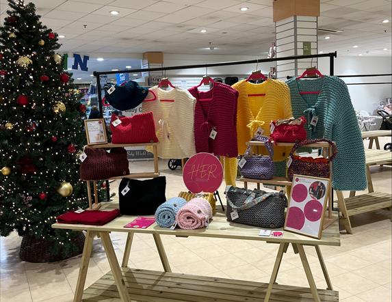 a selection of knitted goods on display beside a christmas tree