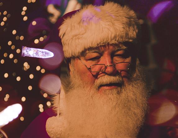 Santa is surrounded by festive lights