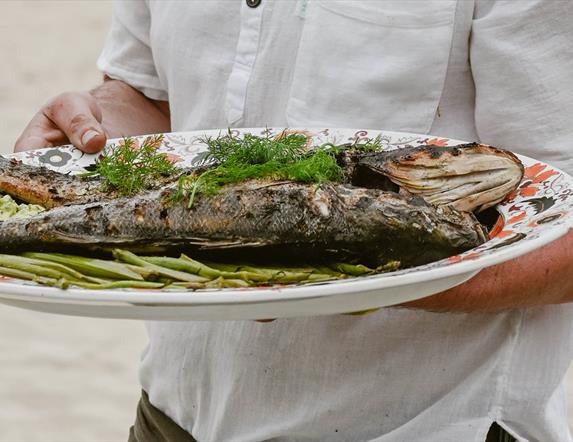 a large plate of freshly smoked fish garnished with greens