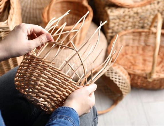 A basket being woven by hand. A collection of these baskets is visible in the background.