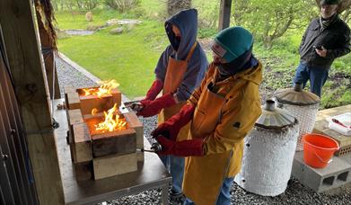 Pots covered with wood shaving being set alight using a blow torch