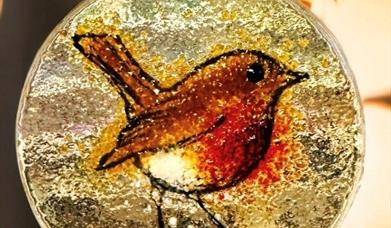 a glass decoration with a picture of a robin in the middle. 