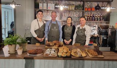 Staff from Bistro at the Courthouse stand behind the restaurants counter, with plenty of bakes and sweet treats in front of them