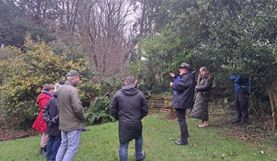 Bob Picken guiding a group dressed in outdoor clothing and hearing stories of the Earl Bishop