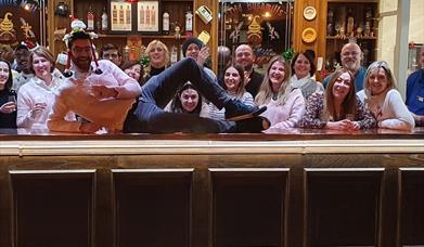 a tour group stand behind a bar