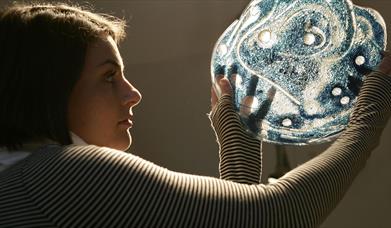 Person examining illuminated glass artwork