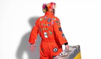 a picture of jitterbug jackson wearing a brightly coloured jumpsuit, facing away from the camera