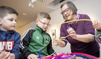 A tutor working with children to make arts and crafts projects