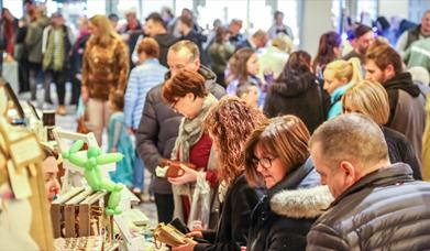 people browsing busy market stalls indoors