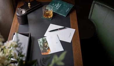 a letter on a pen sit on an old fashioned desk, with various props surrounding