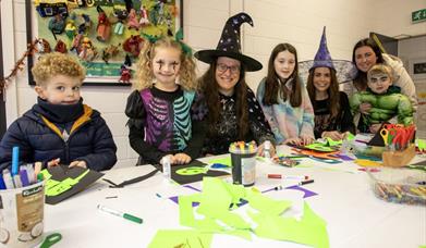 Image of children and faciltators in halloween fancy dress costumes crafting.