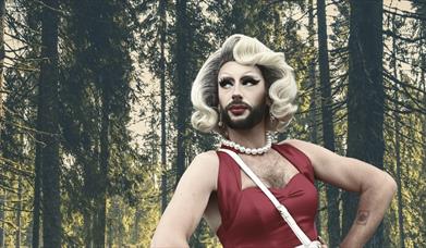 Drag Queen Cherrie On Top pictured against a forest backdrop